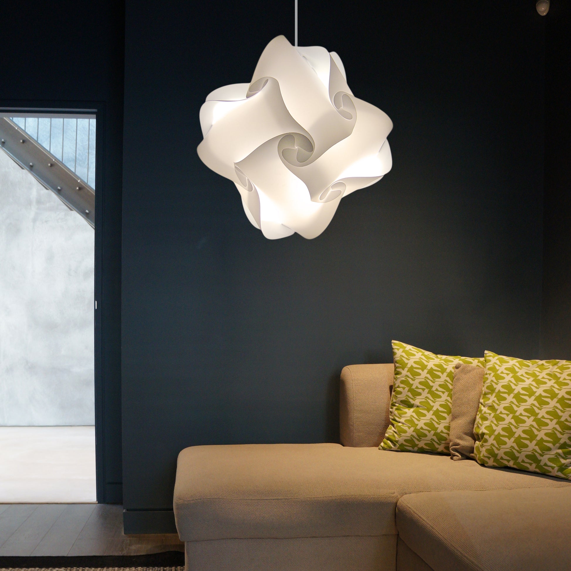 Elegant white swirl lamp hanging over beige couch with patterned pillows in modern living room.