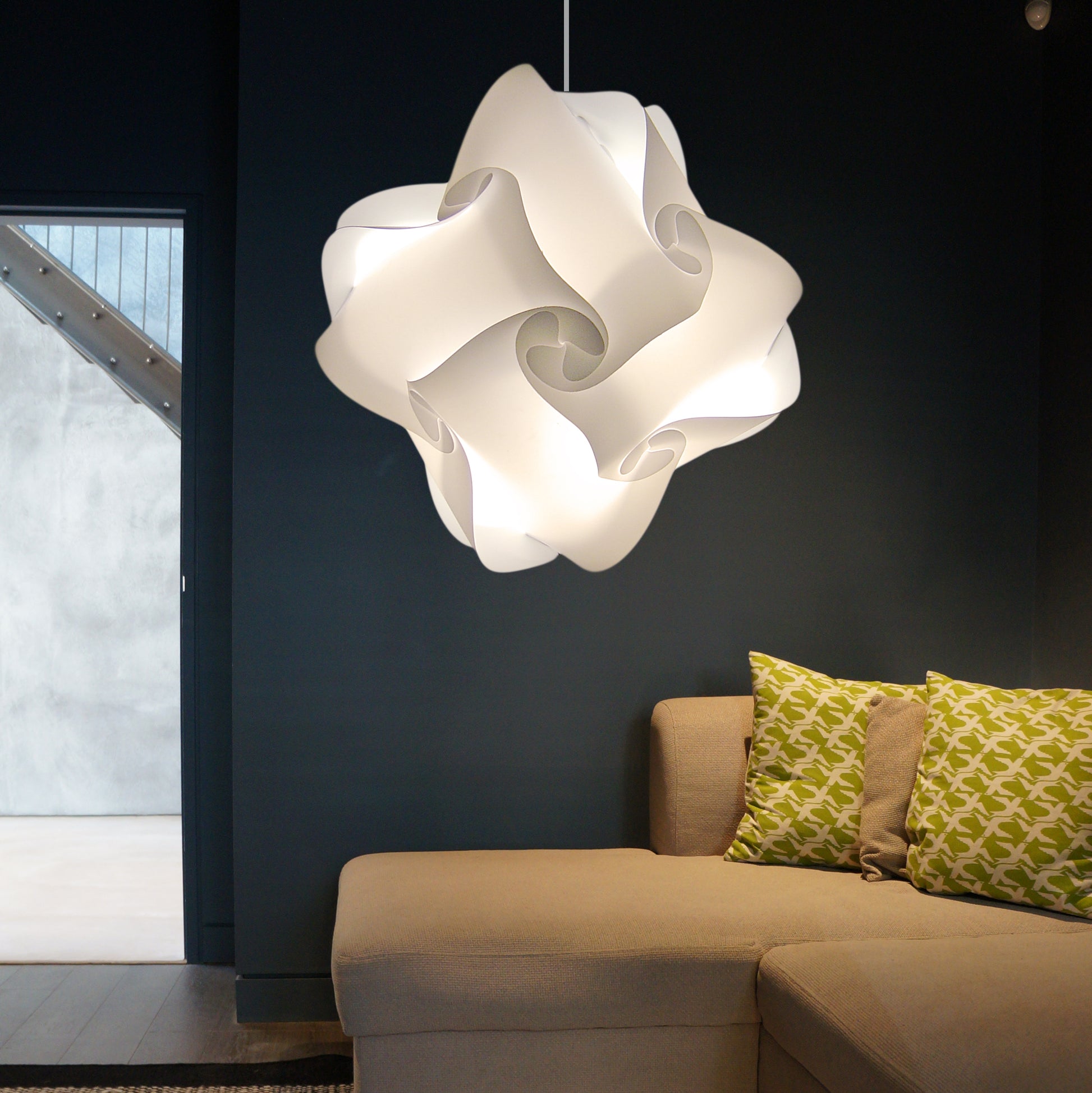 Elegant white swirl-shaped Axelle ceiling lampshade illuminating modern living room with beige sofa and patterned cushions.