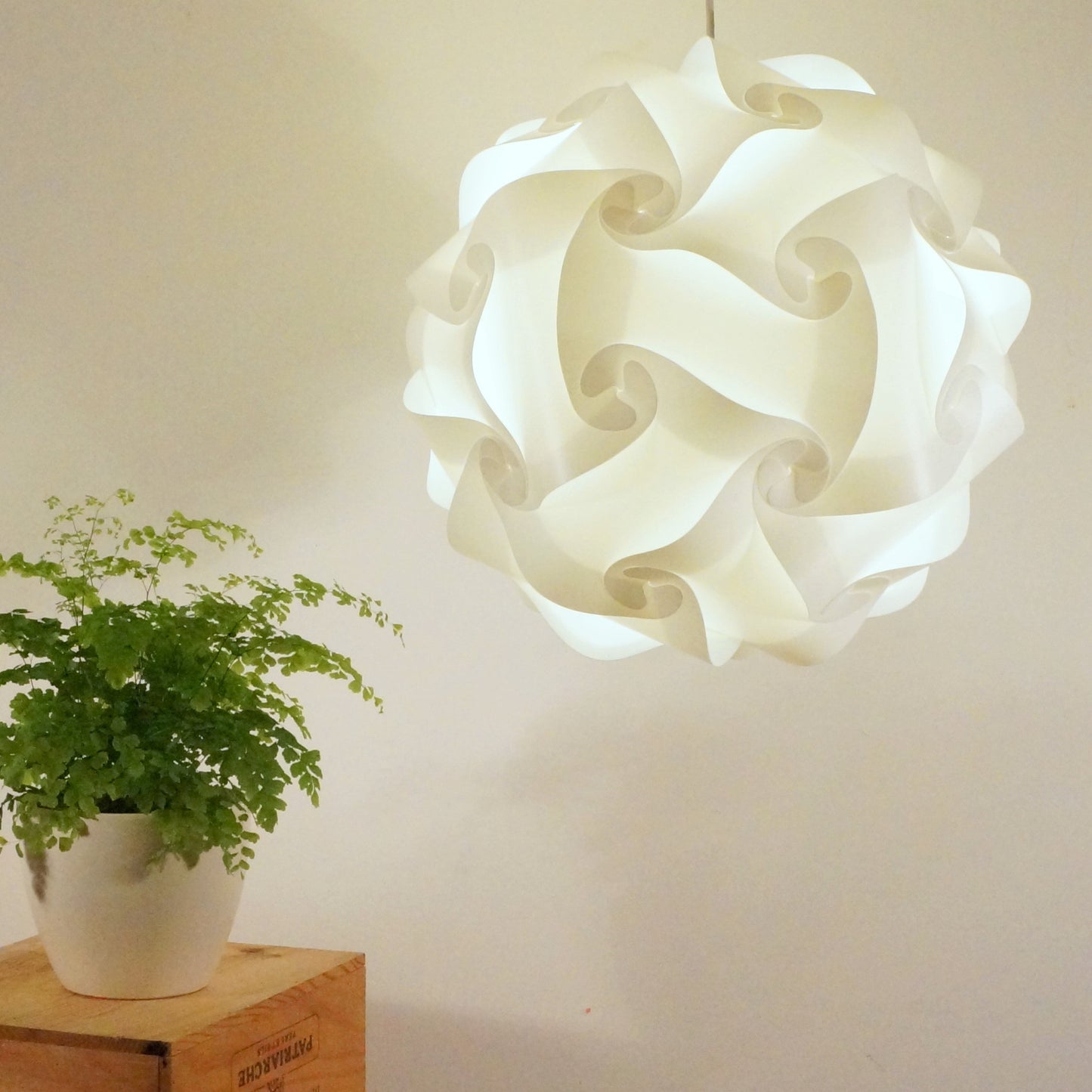 Elegant white spiral lamp shade suspended above potted plant in home decor setting