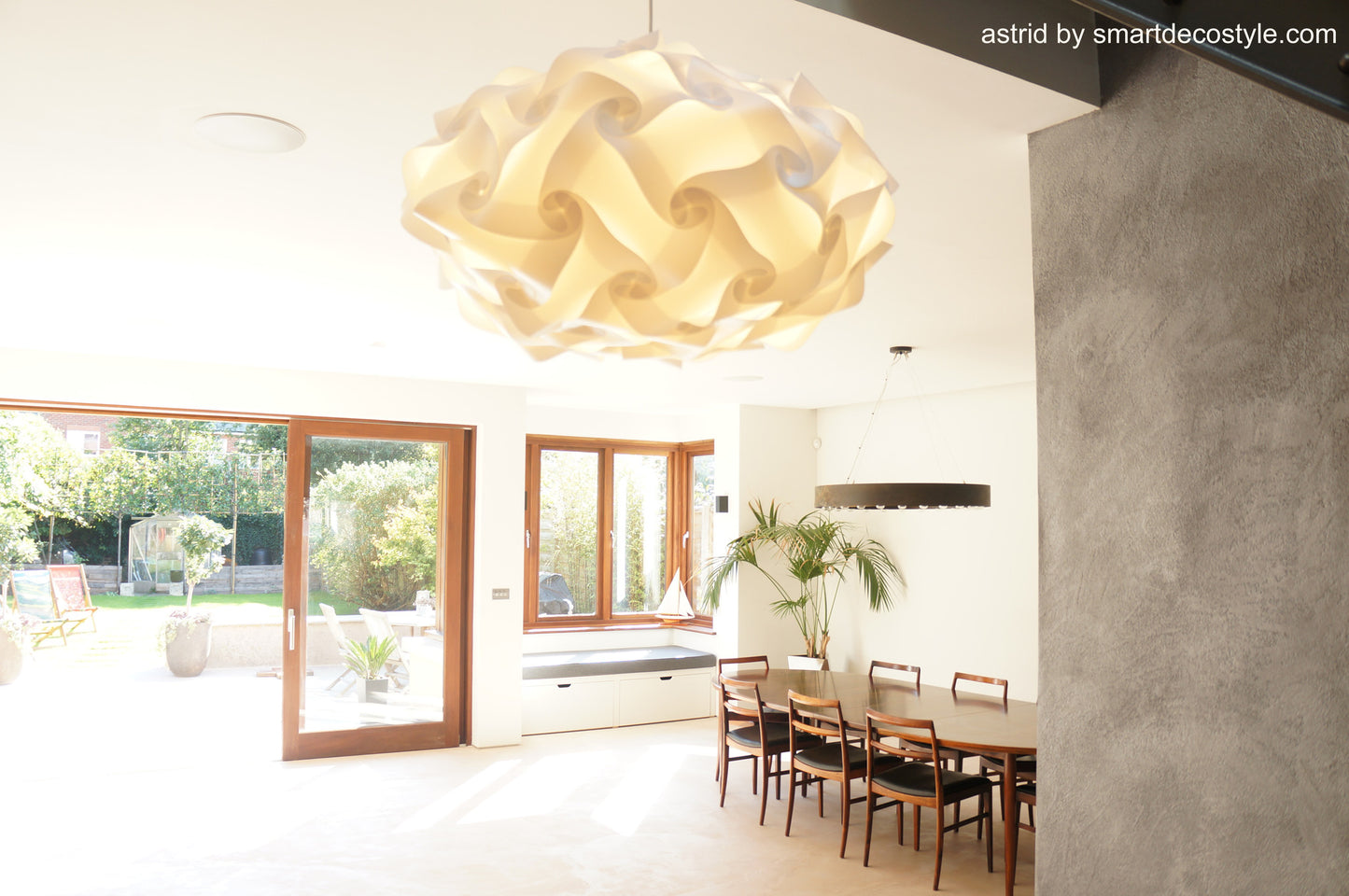 Elegant ivory paper lampshade, Smarty Lamps Astrid Light Shade, suspended from ceiling in modern, minimalist dining room with wood accents and patio view.