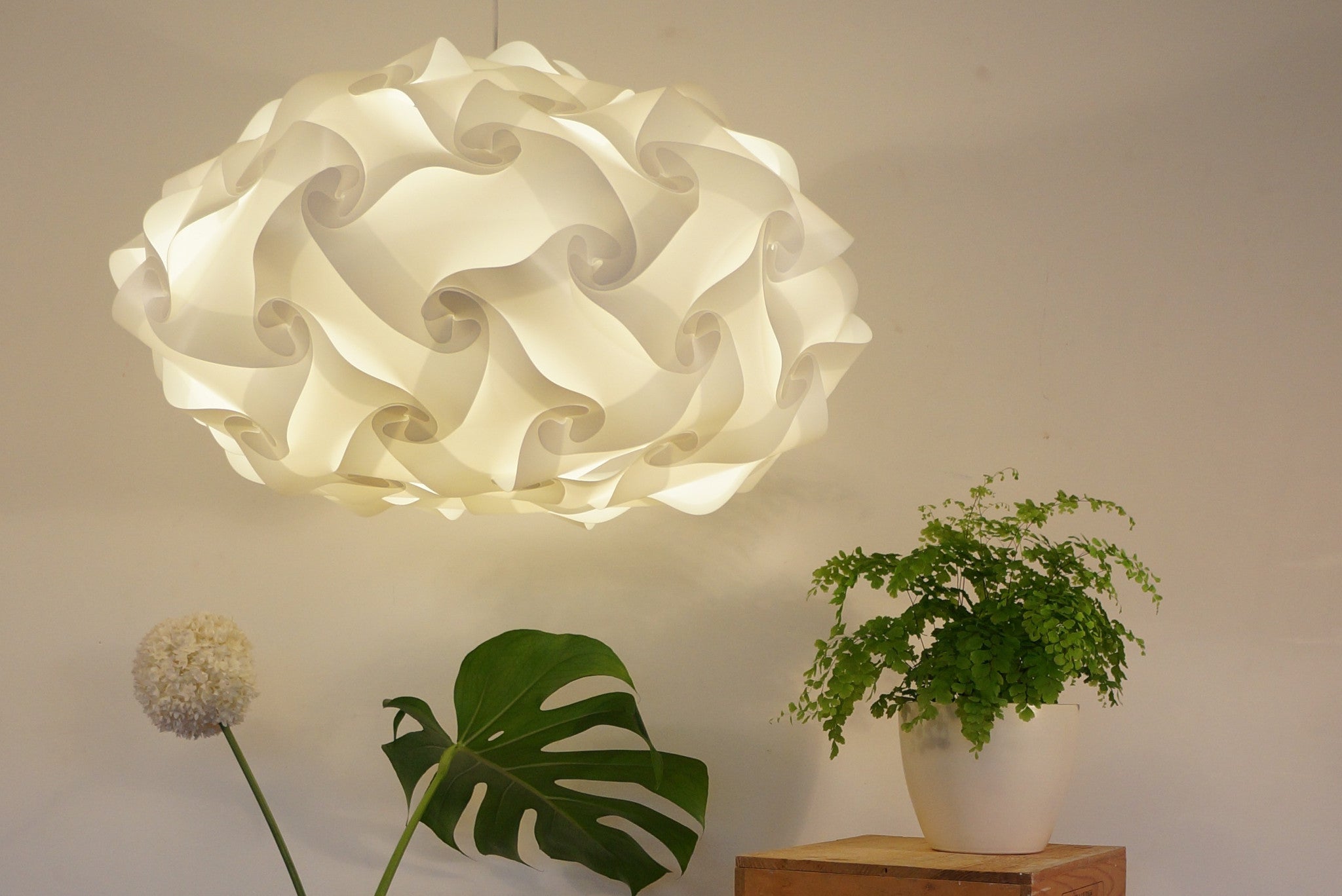 Elegant white pendant lamp shade, vibrant potted plants, minimalist interior decor.
