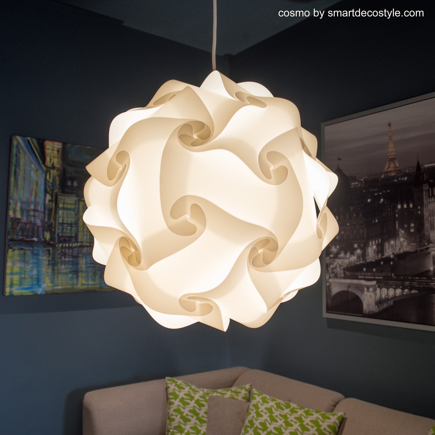 Elegant white floral-shaped lampshade in living room setting. Smarty Lamps Cosmo light fixture with intricate sculptural design. Decorative lighting piece displayed on dark wall with framed artwork.