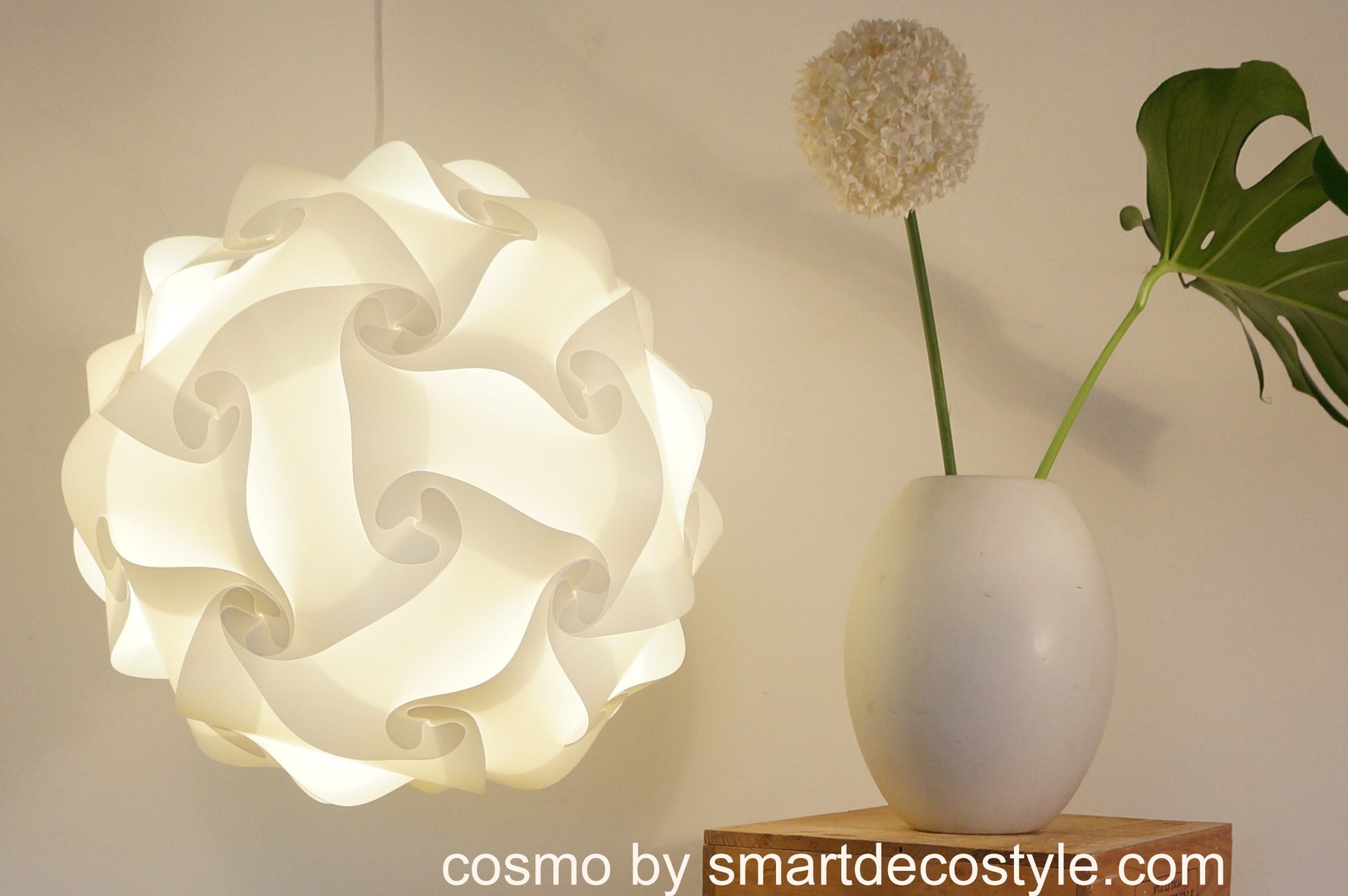 Stylish white swirl lamp shade, white ceramic vase with tropical leaf in minimalist home decor