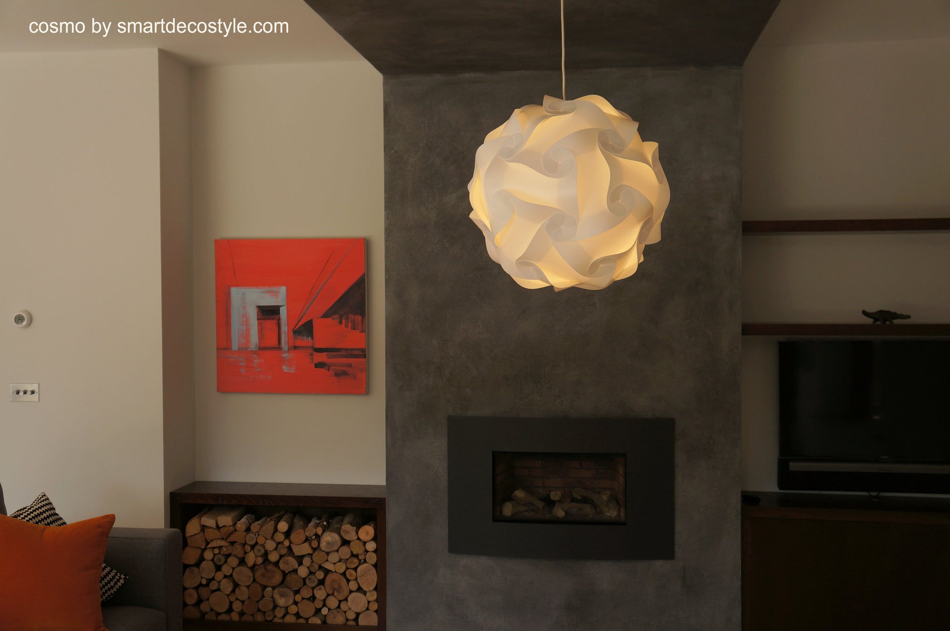 Modern white geometric pendant lamp in a cozy living room with a fireplace and abstract wall artwork.