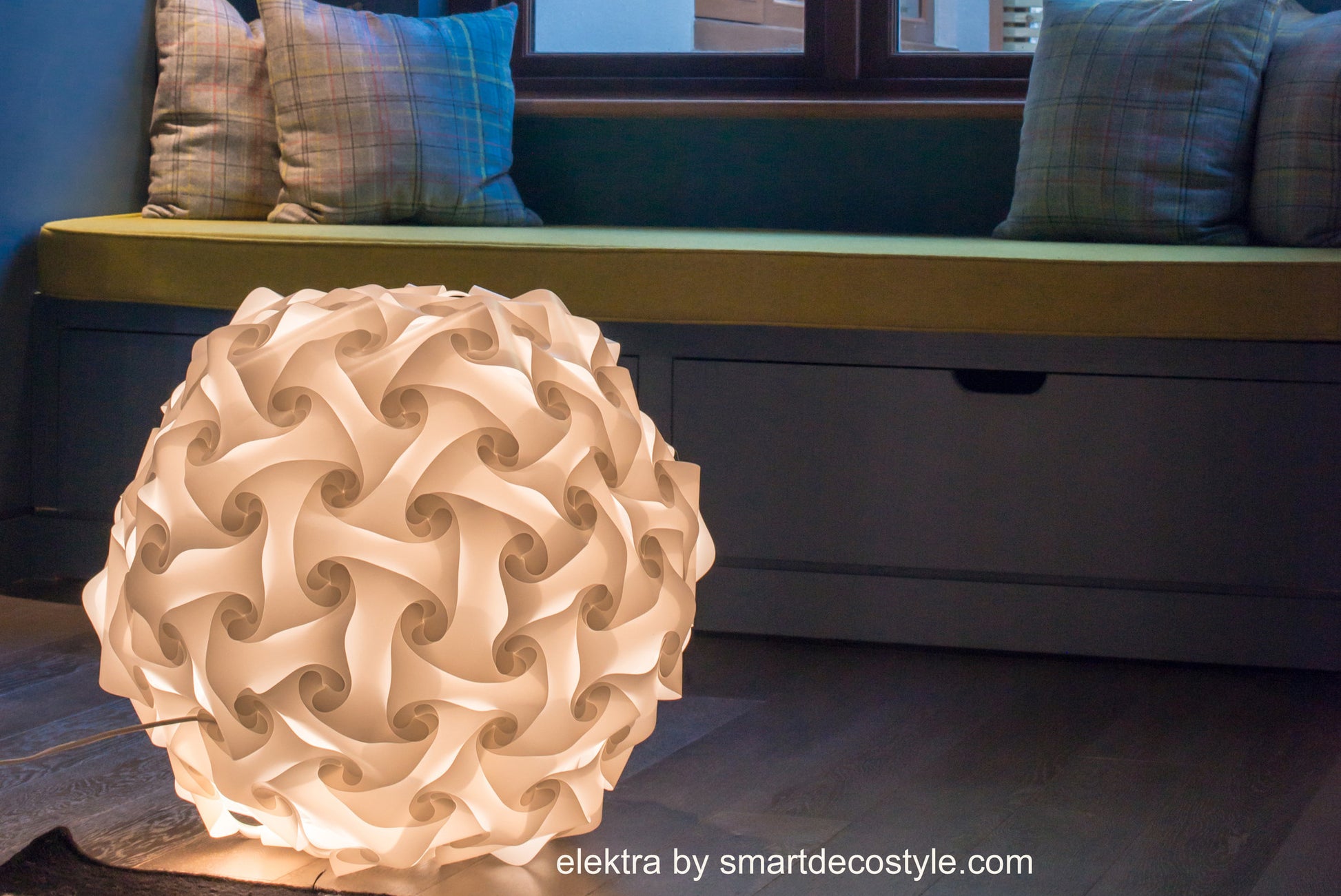 Unique paper art lampshade with intricate swirl design, displayed in a cozy living room setting.