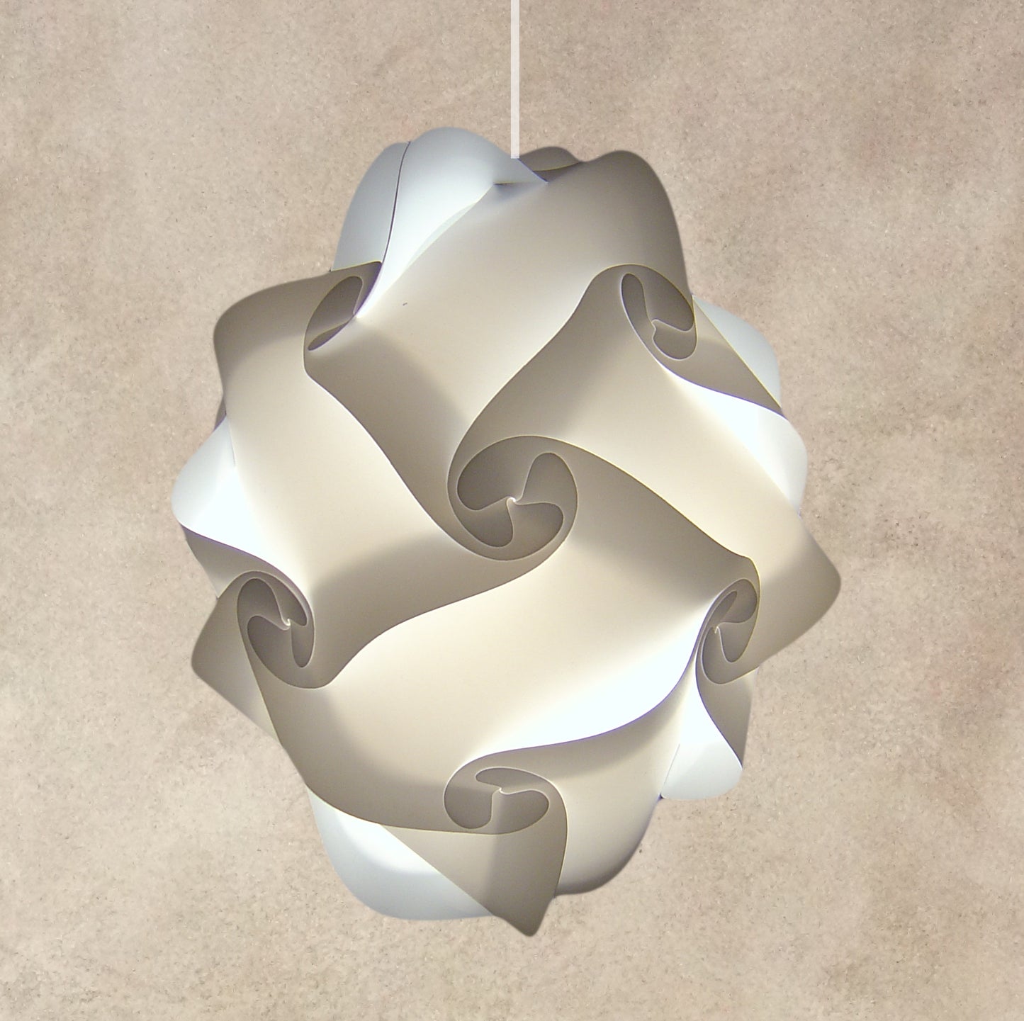 Sleek modern white pendant lamp with abstract swirl design, hanging against a neutral beige background.