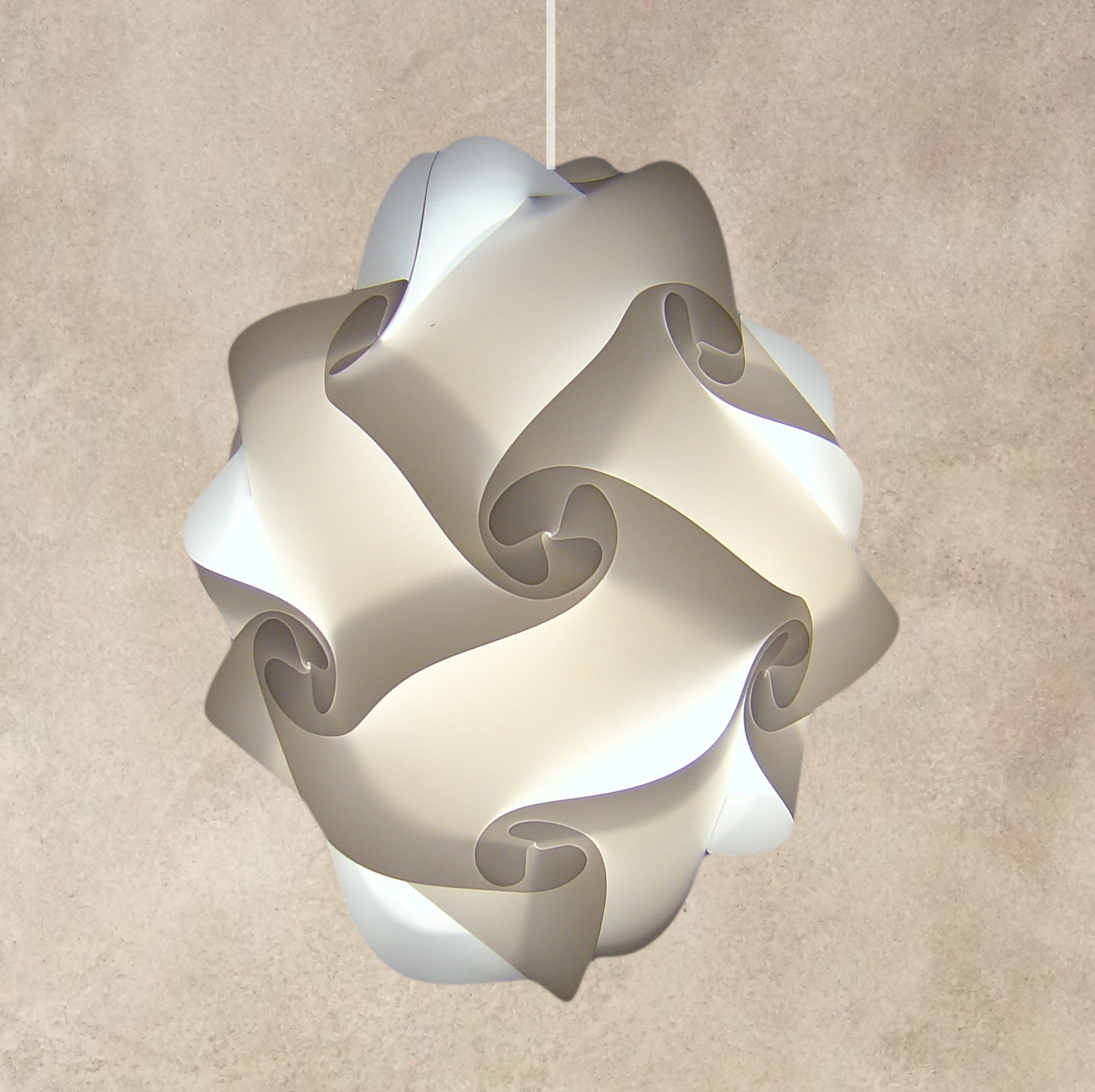 Sleek modern white pendant lamp with abstract swirl design, hanging against a neutral beige background.