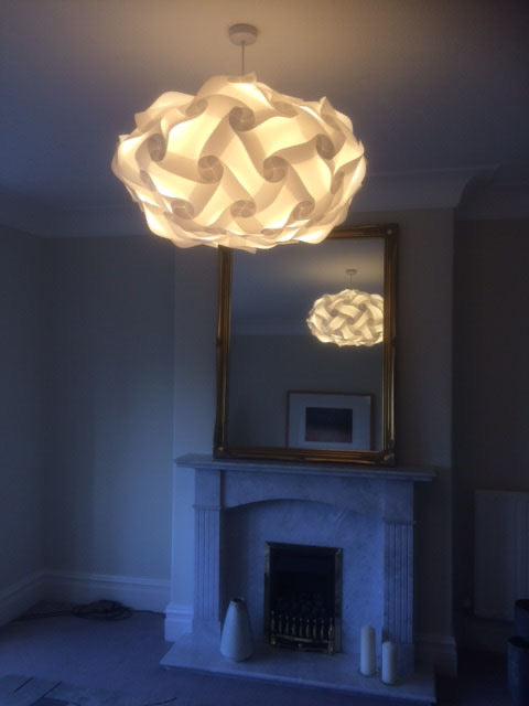 Elegant white woven ceiling lampshade, Smarty Lamps Astrid Light Shade, illuminating a cozy fireplace setting in a stylish home interior.