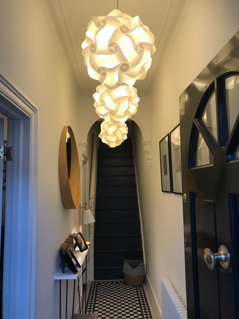 Modern white sculptural pendant light fixture in hallway with black and white tiled floor