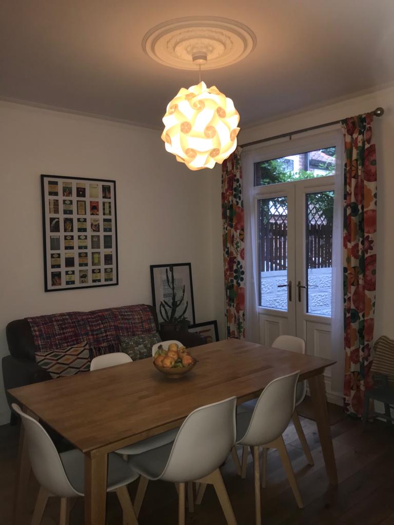 Elegant dining space with wooden table, stylish chairs, and a unique patterned lamp shade suspended from the ceiling.