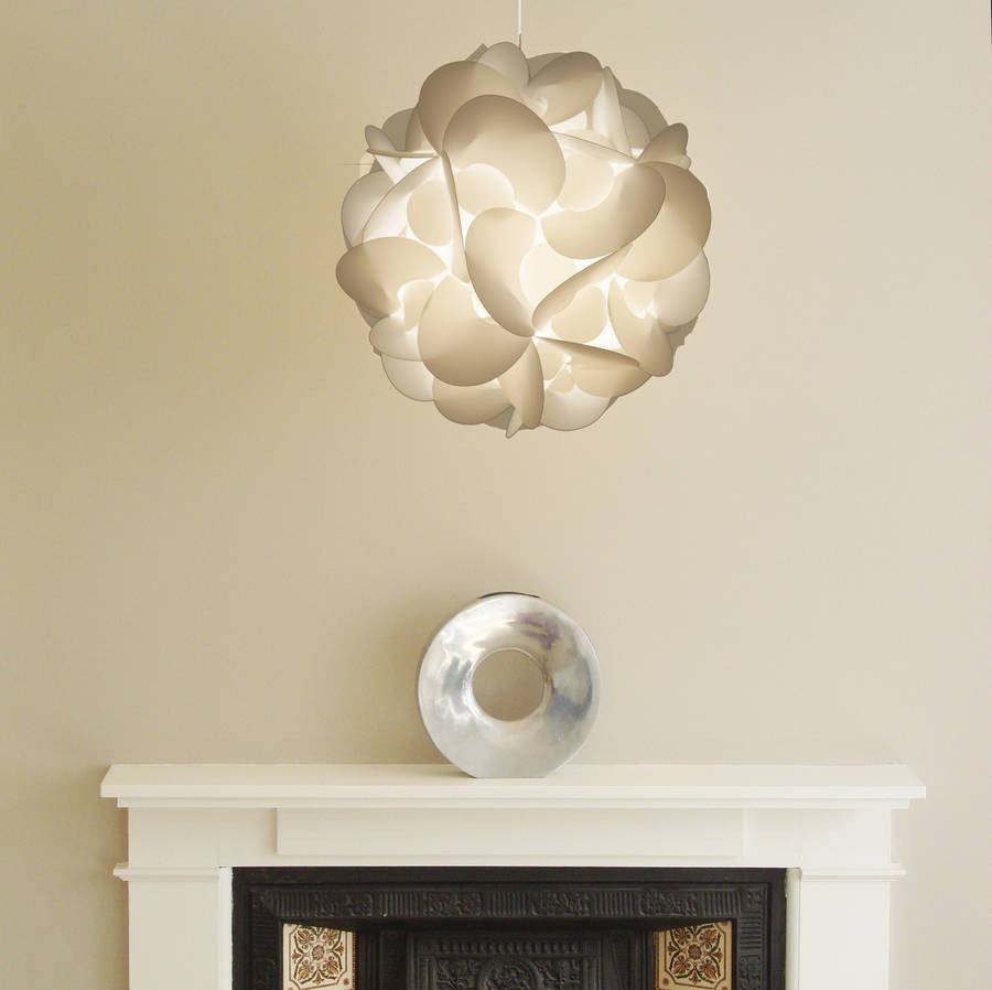 Stylish curved white lampshade suspended from ceiling, decorative glass ornament on white mantelpiece in minimal interior decor